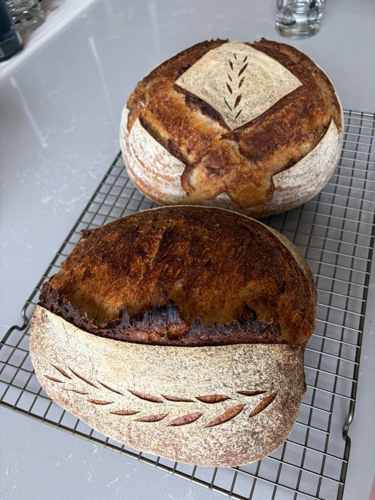 Two artisan sourdough loaves cooling on a wire rack