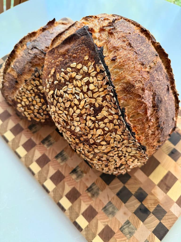 Oat-topped sourdough loaves on a checkered cutting board